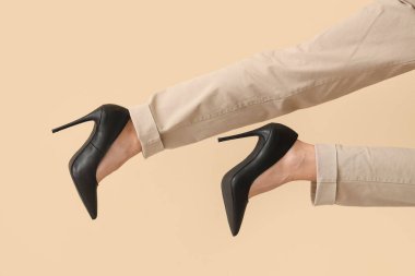 Bej arka planda siyah topuklu kadın bacakları