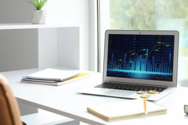 Ofisteki pencerenin yanındaki borsada hisse senedi verileri olan dizüstü bilgisayar.