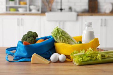 Mutfaktaki ahşap masada farklı taze ürünlerin olduğu alışveriş torbaları.