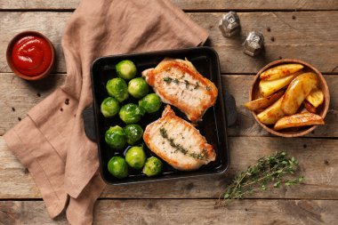 Kızarmış biftekli tava, Brüksel lahanası ve ahşap zemin üzerinde patates.