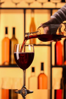 Barda kırmızı şarap şişeden cama dökülüyor.