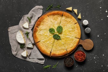 Peynir, yeşillik ve siyah grunge arkaplanlı baharatlı lezzetli pizza.