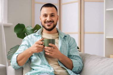 Evde yeşil seramik bardaklı genç adam