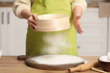 Dişi fırıncı mutfakta un süzüyor. Yakın çekim.