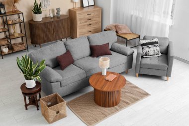 Rahat bir kanepe, oturma odasının içinde lamba ve koltuk olan bir sehpa.