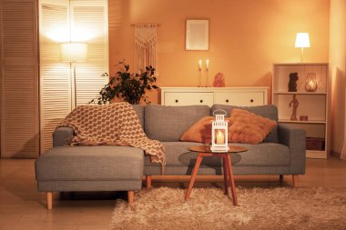 Rahat bir kanepe ve oturma odasının içinde parlayan bir fener olan kahve masası.