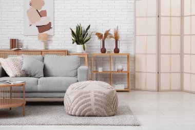 Konforlu kanepe, kahve masası ve pouf oturma odasının içinde.