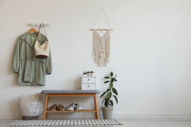 Salonun içinde askıda bank, çanta ve palto var.