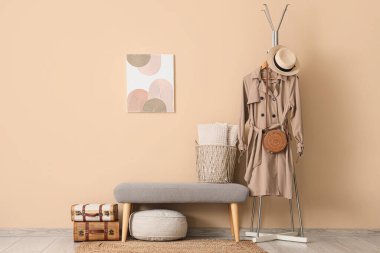 Salonun içinde paltoyla bankta ve askıda.