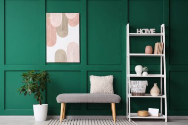 Yastıklı bank, raf ünitesi ve koridordaki bitki örtüsü.