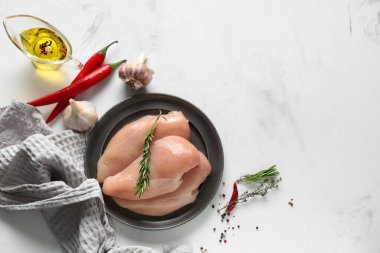 Çiğ tavuk göğsü ve beyaz arka planda farklı baharatlar.