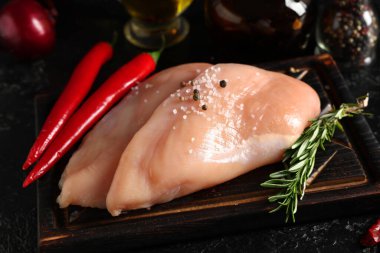 Tahta tahta tahta tahta tahta, çiğ tavuk göğsü, biberiye ve siyah arka planda kırmızı biber.