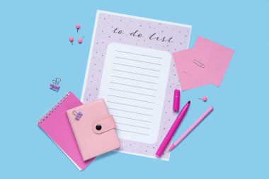 Liste yapmak için boş ve mavi arka planda kırtasiye malzemesi. Üst görünüm