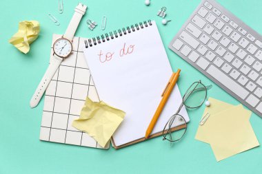 Yapılacaklar listesi boş olan defter, gözlük, kol saati ve turkuaz arka planda kırtasiye malzemesi