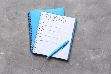 Boş liste ve gri arkaplanda kırtasiye malzemesi olan bir defter. Üst görünüm