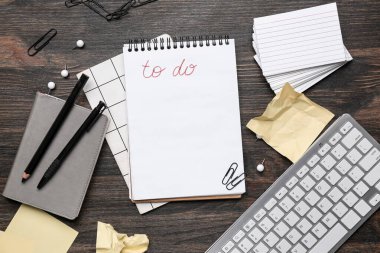 Boş yapılacaklar listesi, klavye ve ahşap arka planda kırtasiye malzemesi olan bir defter. Üst görünüm