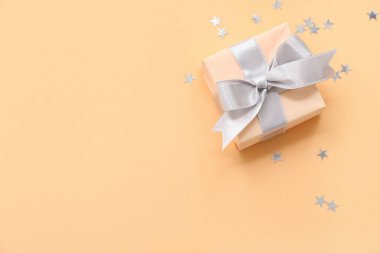 Turuncu arka planda hediye kutusu ve gümüş konfeti.