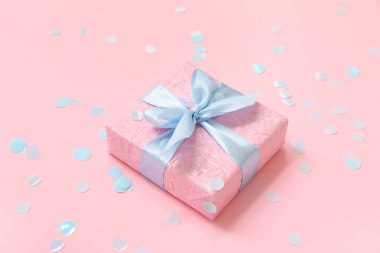 Hediye kutusu ve pembe arka planda mavi konfeti.