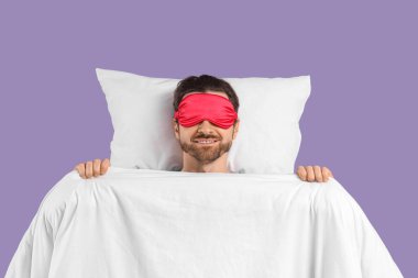 Maskeli yakışıklı genç adam leylak arka planda uyuyor.