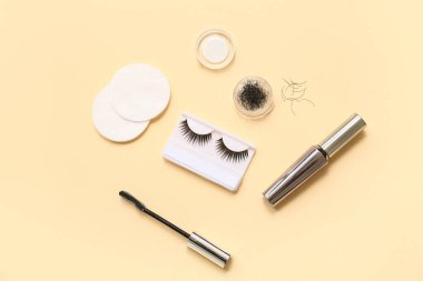 Pamuk yastıklı farklı takma kirpikler ve bej arka planda rimel.