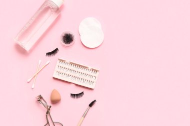 Pembe arka planda araçları olan farklı takma kirpikler