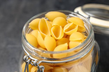 Siyah arkaplanda çiğ koni makarnalı kavanoz, yakın plan.