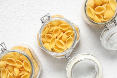 Beyaz arka planda çiğ koni makarnalı kavanozlar