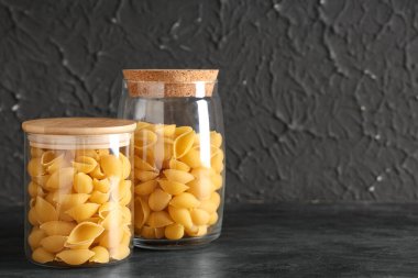 Siyah zemin üzerinde çiğ koni makarnası olan kavanozlar