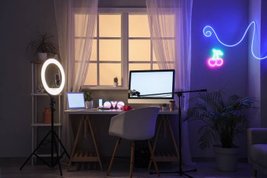Karanlık odada boş bilgisayar monitörü ve dizüstü bilgisayarı olan blog yazarının çalışma alanı