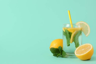 Limonlu su, nane yaprağı ve turkuaz arka planda saman.