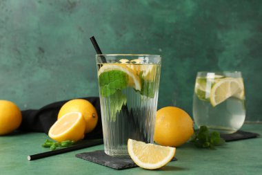 Limonlu su bardakları, yeşil grunge arka planında nane yaprakları ve pipetler