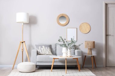 Oturma odasındaki vazoda içinde okaliptüs dalları olan rahat bir kanepe ve sehpa.