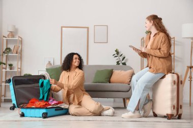 Güzel, genç, mutlu bayan arkadaşlar evde bavullarını topluyor.