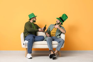 Yeşil sakallı, leprikon şapkalı genç adamlar ellerinde bira şişeleri ve sarı duvarın yanındaki kanepede oturuyorlar. Aziz Patrick Günü kutlaması