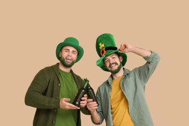 Yeşil sakallı, leprikon şapkalı genç adamlar bej arka planda bira şişeleri tutuyorlar. Aziz Patrick Günü kutlaması