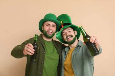 Yeşil sakallı, leprikon şapkalı mutlu genç adamlar bej arka planda bira şişeleri taşıyorlar. Aziz Patrick Günü kutlaması