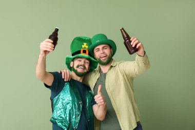 Yeşil sakallı, yeşil sakallı, leprikon şapkalı genç adamlar ellerinde bira şişeleri ve yeşil arka planda baş parmak hareketi gösteriyorlar. Aziz Patrick Günü kutlaması