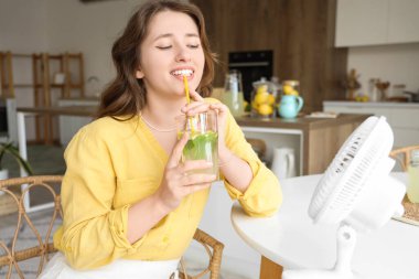 Mutfaktaki masada lezzetli limonata içen genç bir kadın.