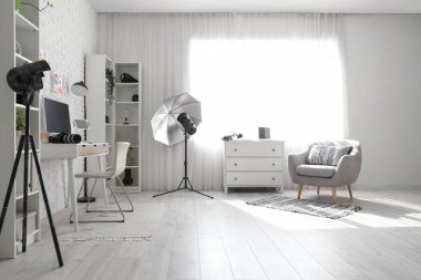 Modern stüdyoda bilgisayar, ışıklandırma ekipmanı ve fotoğraf makinesi olan fotoğrafçı işyeri