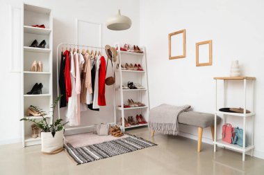 Kıyafet rafları ve gardıroptaki beyaz duvarın yanında farklı kadın ayakkabıları olan raflar.