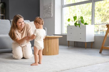 Mutlu anne bebeğiyle evde yürümeyi öğreniyor.