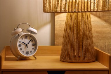 Gece yatak odasındaki masasında parlayan lamba olan çalar saati kapat.