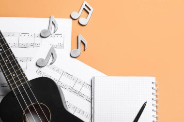 Ukulele ile kompozisyon, müzik sayfaları ve renk arkaplanı üzerine not defteri