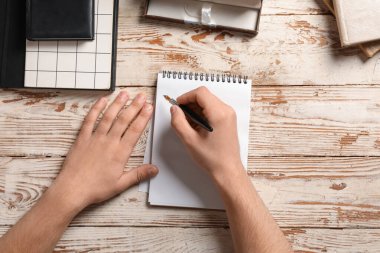 Defterleri olan erkek eller ve tahta arka planda dolmakalem, yakın plan.