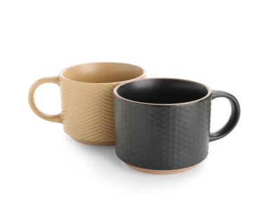 Beyaz arkaplanda bej ve siyah seramik kupalar