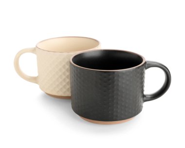 Beyaz arkaplanda bej ve siyah seramik kupalar