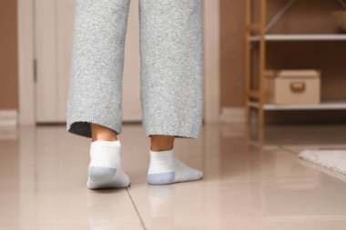Pantolon giymiş kadın bacakları ve evde ısıtmalı çoraplar.