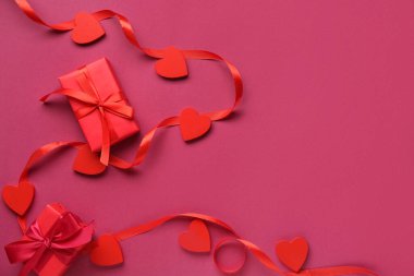 Kırmızı kalpli kurdele ve pembe arka planda hediye kutuları. Sevgililer Günü kutlaması
