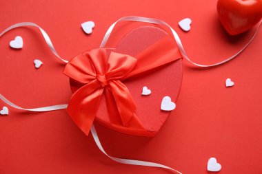 Kırmızı arka planda kupa ve kurdeleli hediye kutusu. Sevgililer Günü kutlaması