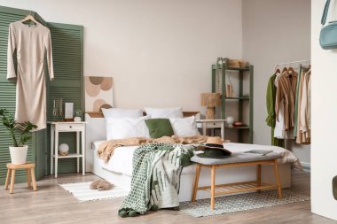 Modern yatak odasındaki rahat yatak ve askılar.